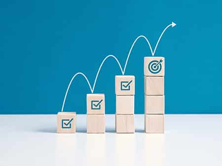 Steps for goal achievement and business success. Project tracking and task completion. Managing project timeline. Checkmark and target goal  symbols on wooden cubes.